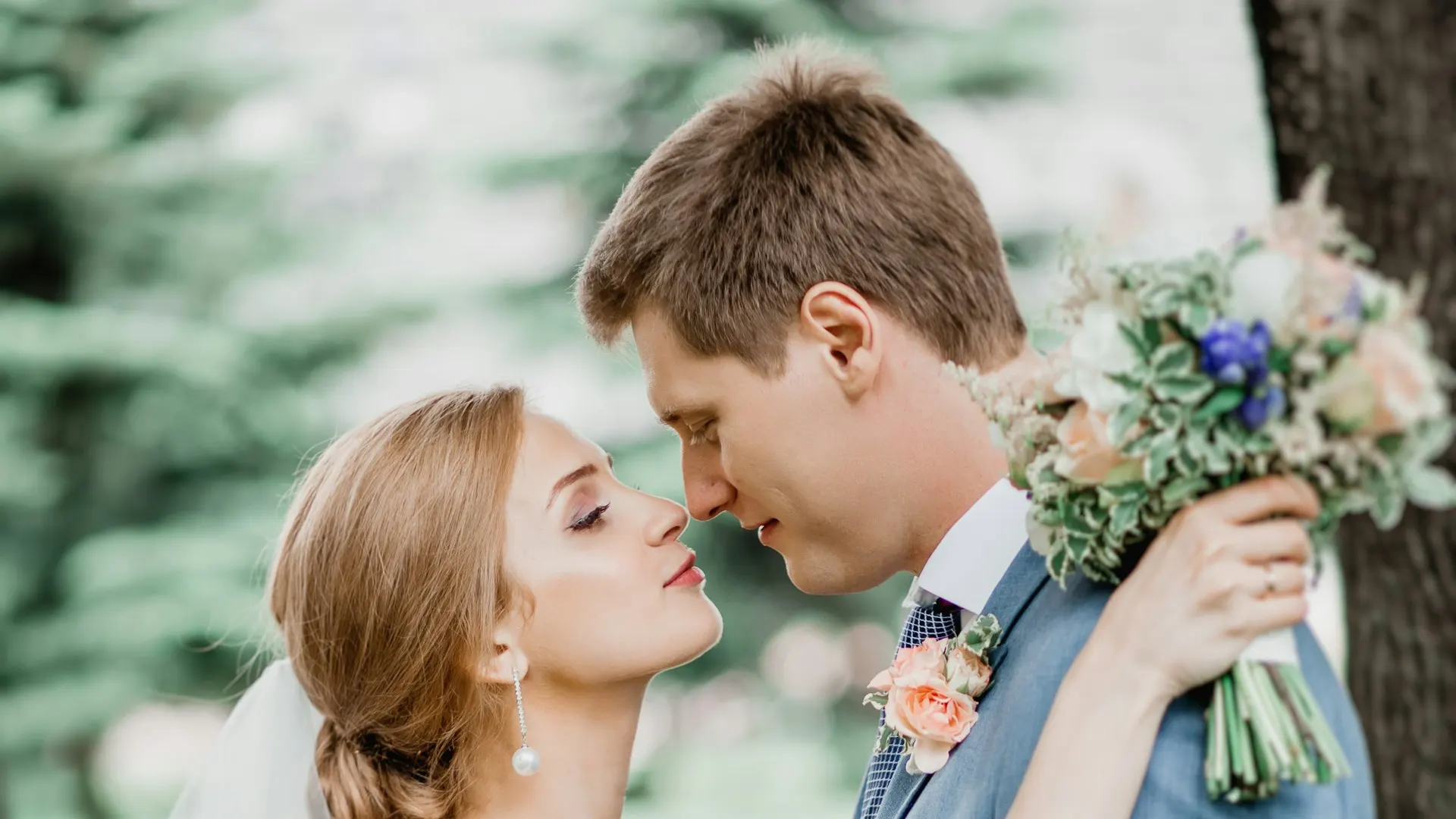 Gelin ve damat yeşil bir bahçede öpüşüyor